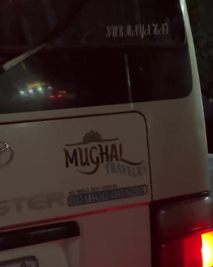 A Mughal Travels Coaster at night, rear view with the company name