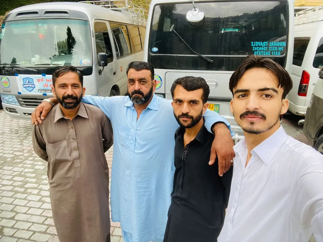 Mughal Travels drivers and staff standing in front of a Coaster